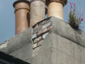 Chimney stack observed during a building inspection with missing render and weeds growing in it