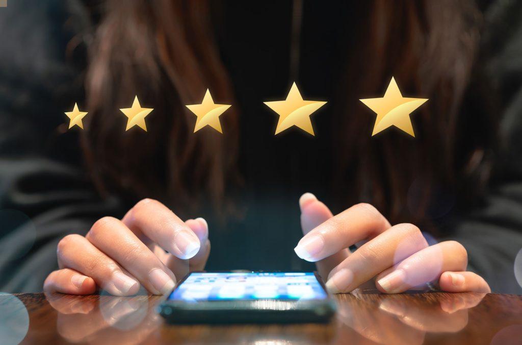 female looking at mobile phone and giving 5 star rating