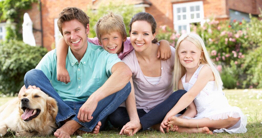 Family sitting on a lawn at home with their dog