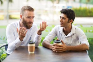 Two males drinking coffee and having a discussion