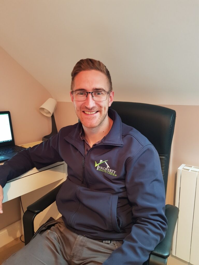 White male with glasses sitting at a desk